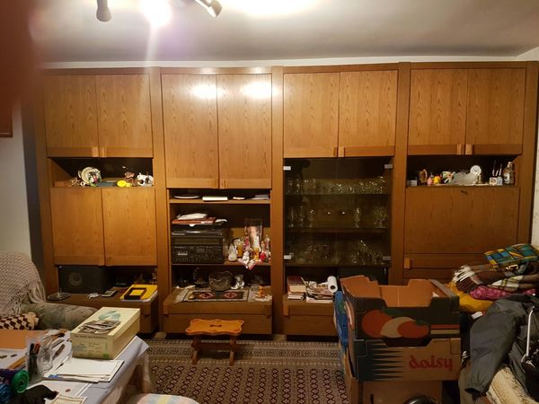 Großer, rustikaler Wohnzimmerschrank aus Holz mit Glastüren, Dekoration und Umzugskartons.