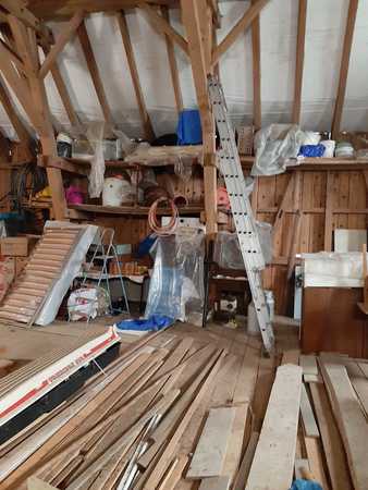 Dachboden mit Holzlatten, Werkzeug, Leiter und Baumaterial für Renovierungsarbeiten.