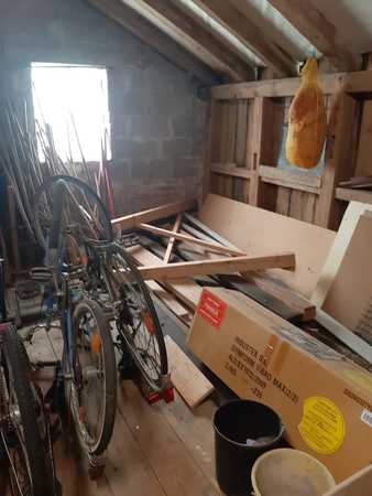 Dachboden mit alten Fahrrädern, Holzbalken, Kartons und Schinken an der Decke.